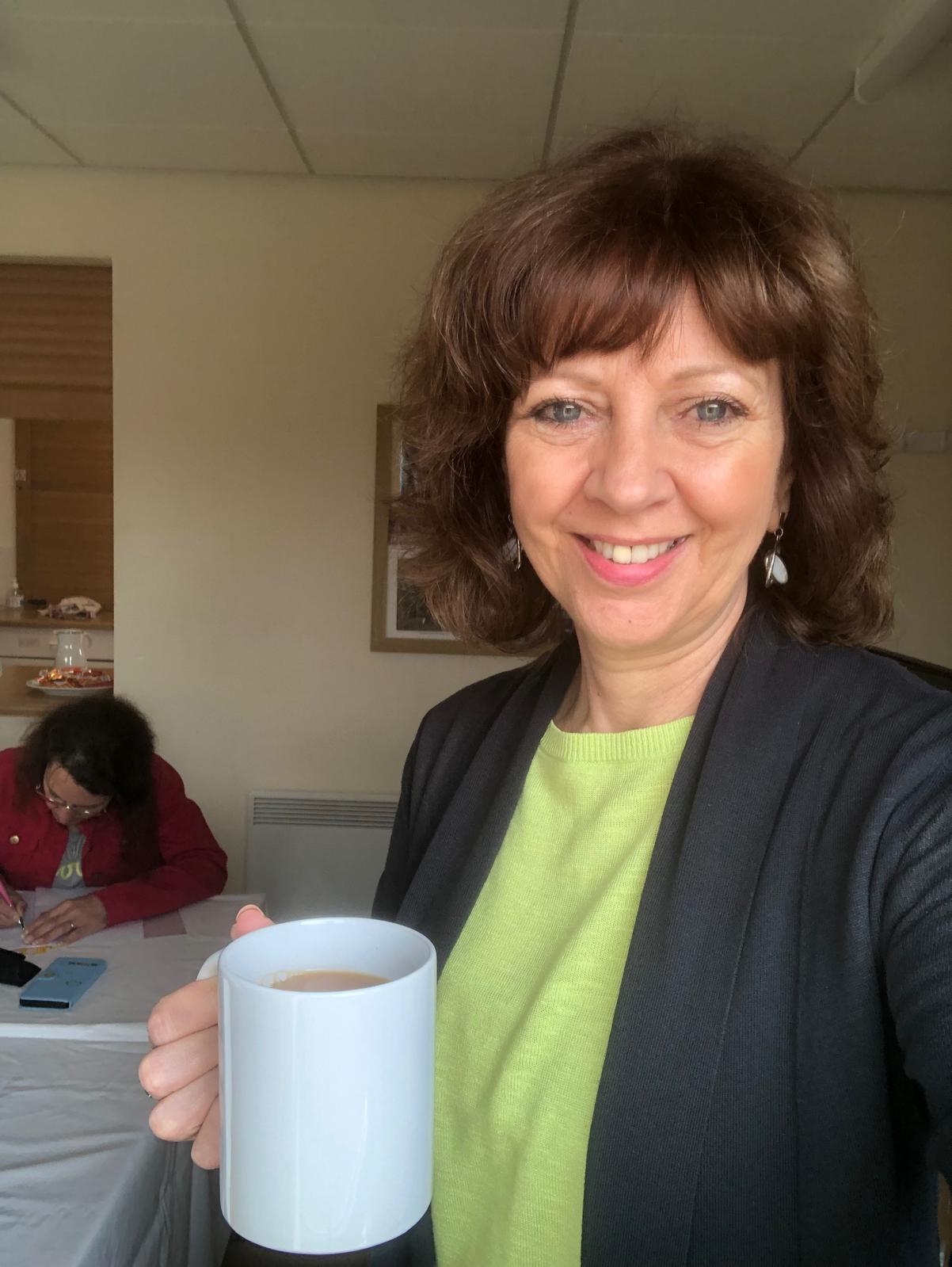 Gillian enjoying her work holding a mug of tea
